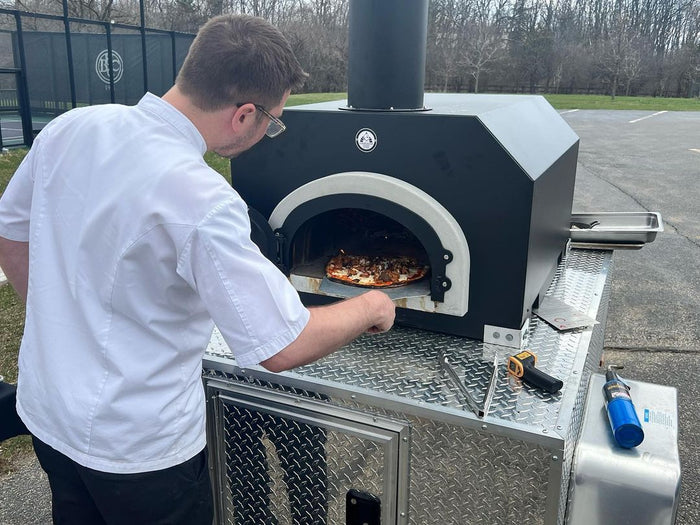 CBO-750 Tailgater Wood Fired Pizza Oven  - Lifestyle Image Cooking Pizza   